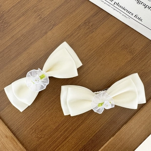 Détail de barrettes à cheveux à nœud crème avec roses en résille sur bois
