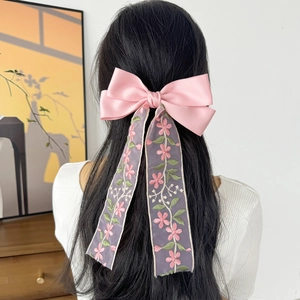 Dettaglio di fiocco in raso rosa con nastri in rete viola ricamati su capelli lunghi