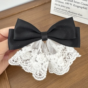 Detailed view of the double-layer black satin bow clip with white floral embroidery lace