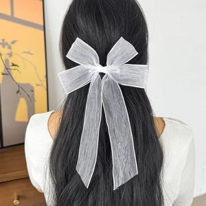 Elegant large white mesh bow hair clip with long ribbons worn on wavy black hair