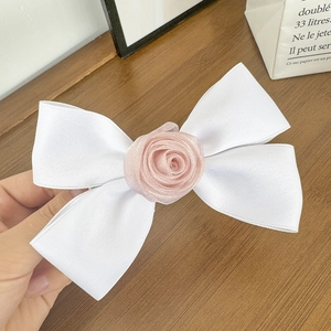 Dettaglio fermaglio per capelli con fiocco in seta bianca e delicata rosa in organza