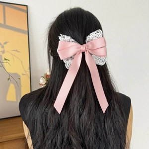 Pink satin bow hair clip with white lace trim shown on long straight hair from behind