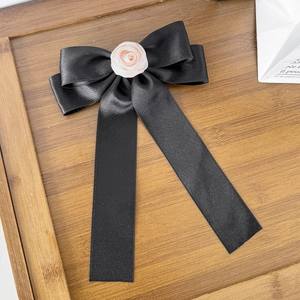 Détail d'un nœud papillon en satin noir avec rose en tissu et longs rubans élégants