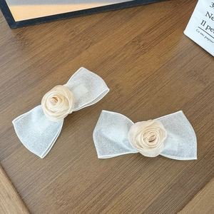 Detailansicht der champagnerfarbenen Rosen-Haarspangen auf dunklem Holztisch