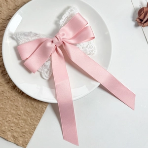Detailed view of a pink satin bow hair clip with white lace and long elegant streamers