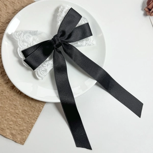 Detailed close-up of a black silk ribbon bow with white lace on a ceramic plate
