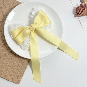 Close-up of bright yellow satin bow with white lace on a white decorative ceramic plate