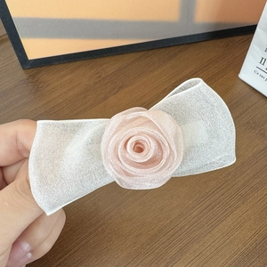 Nahaufnahme einer zarten Haarklammer aus Netzgewebe mit einer kleinen rosa Stoffrose