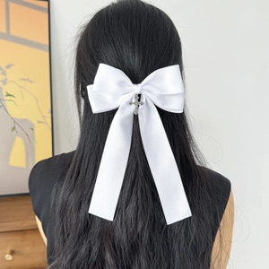 Elegant white satin bow hair clip with silver cross pendant and long tassel on black hair