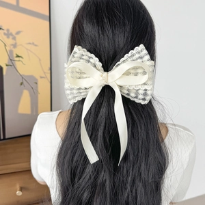 Barrette nœud en dentelle beige élégante portée sur de longs cheveux noirs lisses