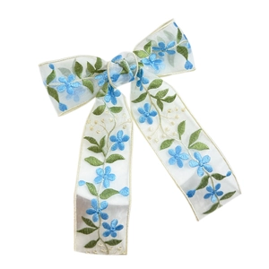 Fermaglio a fiocco in pizzo con ricamo a fiori blu su organza bianca traslucida