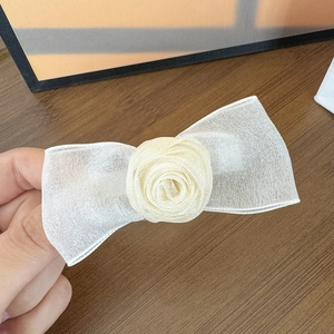 Eleganter Haarclip mit Netzschleife und cremefarbener Rose auf Holzuntergrund