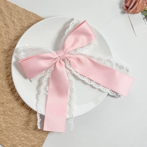 Close-up of pink satin ribbon bow with white lace trim and elegant dual-layer structure