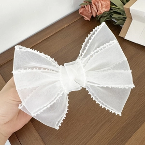 Détail d'une grande barrette à cheveux nœud en tulle blanc avec broderies de perles