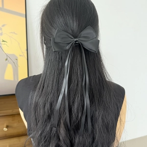 Gros plan sur un nœud de cheveux en satin noir avec de longues et élégantes franges
