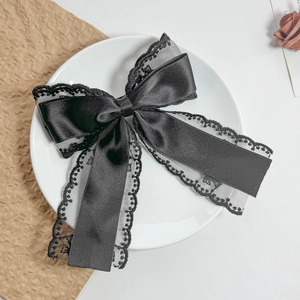 Close-up of black lace and satin bow hair clip on a white decorative ceramic plate