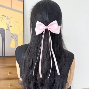 Barrette à cheveux en satin rose avec nœud et rubans portés sur de longs cheveux raides