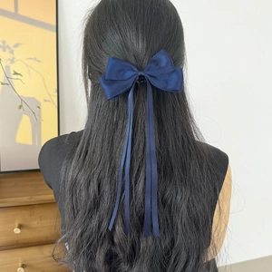 Vue arrière détaillée d'une barrette à cheveux nœud bleu marine avec de longs rubans