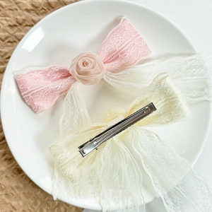 Elegant Korean style lace flower bow hair clips in pink and beige on white ceramic plate