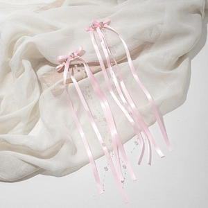 Detail of pink bow hairpins with long ribbon streamers and heart-shaped beads for girls