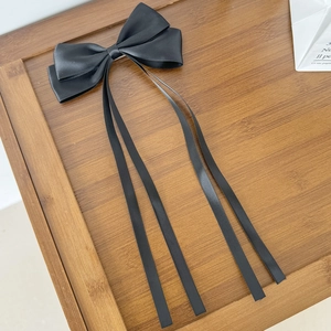 Détail d'un nœud papillon en satin noir avec de longs rubans sur fond de bois