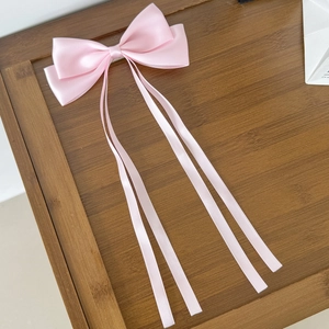 Gros plan détaillé d'une barrette à nœud en satin rose avec de longs rubans fluides