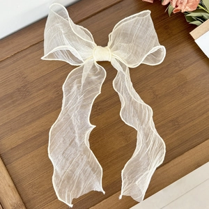 Detail of elegant light beige organza bow hair clip with flowing long ribbons