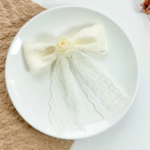 Close-up of lace bow hair clip with handmade rose flower and long elegant tassels