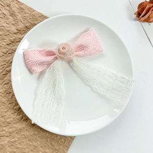 Pink and white lace bow hair clip with silk rose on a decorative ceramic plate