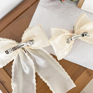 Elegant off-white bow hair clips with scalloped edges and pearl luster fabric
