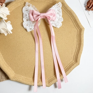 Dettaglio del fiocco per capelli in raso rosa con pizzo bianco su vassoio beige