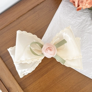 Elegant beige satin bow hair clip with a pink rose flower and green ribbon accents