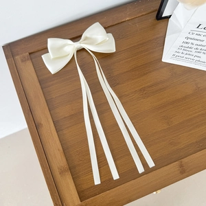 Gros plan du nœud en satin crème avec de longs rubans sur une table en bois rustique