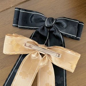 Elegantes Set aus Haarspangen mit Satin-Schleifen in Schwarz und Champagner auf Holzdekor