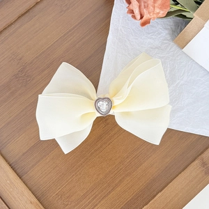 Détail d'une barrette à cheveux en tulle crème avec un cœur en diamant scintillant