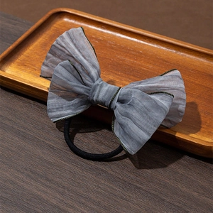 Détail du chouchou nœud en tulle gris montrant la texture du tissu et l'élastique