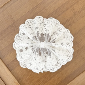 Chouchou en dentelle blanche avec broderie florale et bords festonnés sur bois
