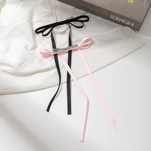 Barrettes à cheveux avec nœud en ruban rose et noir et longs rubans sur tissu blanc