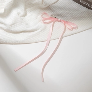 Détail d'une barrette à cheveux en satin rose avec de longs rubans élégants
