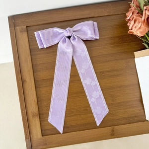Detail der lavendelfarbenen Haarschleife mit Blumenmuster und Wellenrand-Design