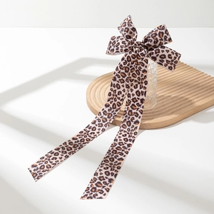 Dettaglio di un grande fermaglio per capelli con fiocco leopardato e lunghi nastri chic