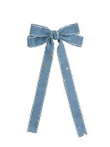 Detail of denim bow hair clip with white wavy embroidery and golden star patterns