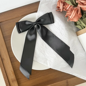 Detailed close-up of premium black satin ribbon bow hair clip with elegant long streamers