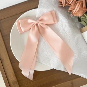 Detailed view of light pink satin bow hair clip with long ribbons on white tray