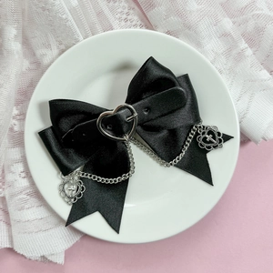 Détail de la pince à cheveux nœud noir gothique avec boucle cœur et pendentif croix
