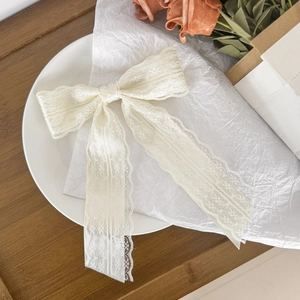 Close-up of cream lace bow hair clip featuring intricate floral crochet patterns and texture