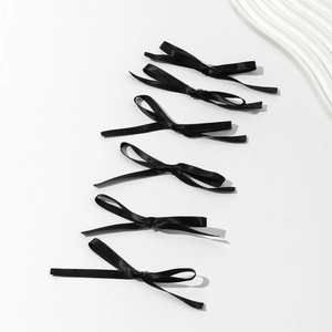 Set of six elegant black satin bow hair clips with long ribbons in a minimalist arrangement