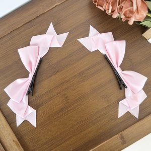 Detail of pink satin bow hair clips on a wooden tray with a gentle aesthetic