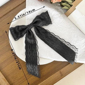 Detail view of a black lace bow hair clip with ribbons and size measurements