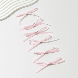 Set of six light pink satin bow hair clips for women arranged on a minimalist background